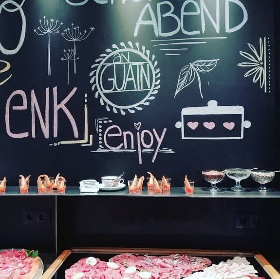 Buffet mit kalten Vorspeisen vor einer Wandtafel mit handgeschriebenen Worten und Zeichnungen.