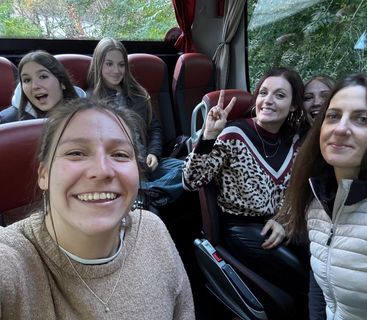 Fröhliche Gruppe von Frauen in einem Bus, die in die Kamera lächeln.