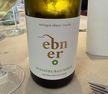 Flasche Weißburgunder Weißwein von Weingut Ebner auf einem Tisch mit Glas und Besteck