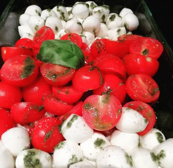 Tomaten und Mozzarellakugeln mit Basilikum und grünem Dressing